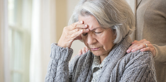 Elderly woman holding her head in pain.