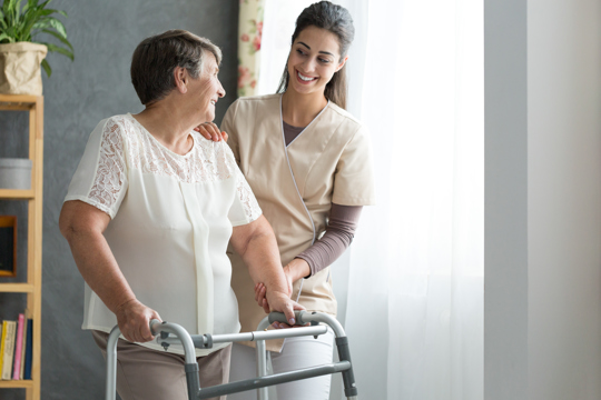 Nurse assisting elderly woman with walking.