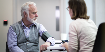 Elderly man having his blood pressure checked by a professional.