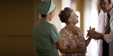 Doctor and nurse speaking with elderly patient.