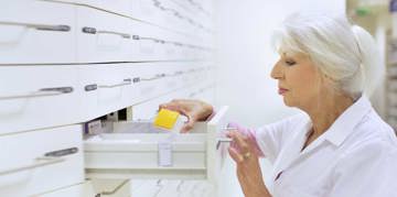 Pharmacist taking medicine from a drawer.