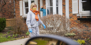 Masked woman standing in front of a house