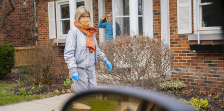 Masked woman standing in front of a house