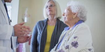 Two elderly women talking to a doctor.