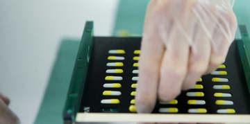 Gloved hand sorting pills.