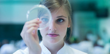 Woman looking at a microscope lens.