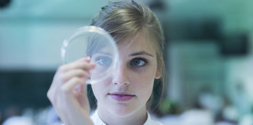 Woman looking at a microscope lens.