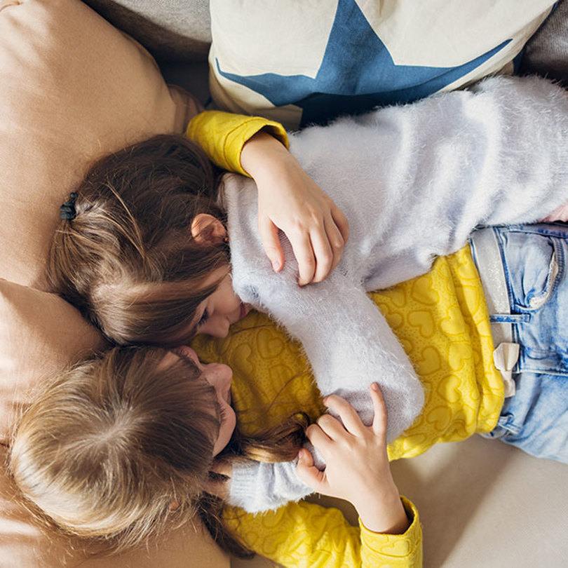Children hugging on sofa.