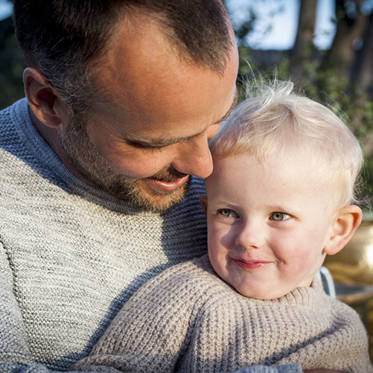 Father hugging son and smiling.