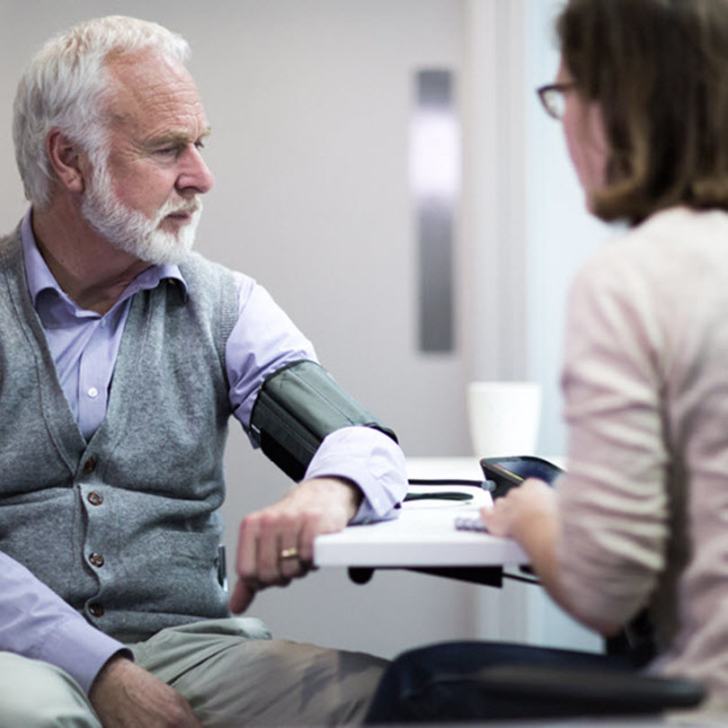 Elderly man getting his blood pressure checked by a professional.