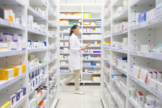 A pharmacist walking among medicines shelves
