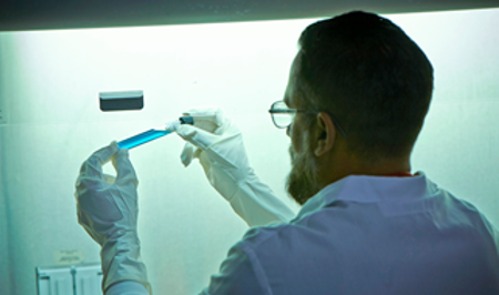 Scientist holding blue vial.