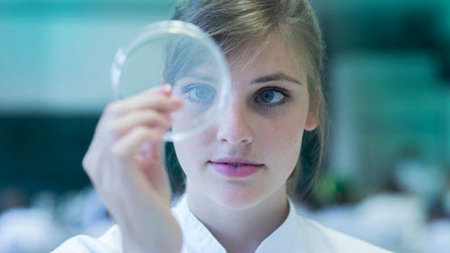 Woman looking at a microscope lens.