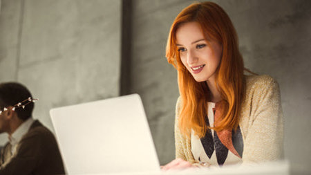 Woman with red hair using a laptop.