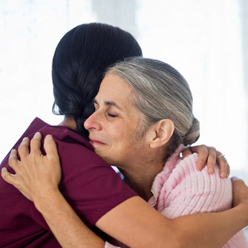 A nurse hugging an elderly patient
