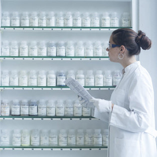Pharmacist looking at pills on shelves.