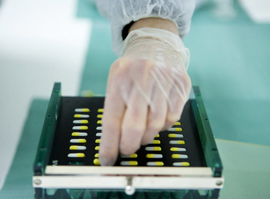 Hand grabbing a pill from a box.