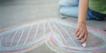 Child drawing a heart on the floor using chalk