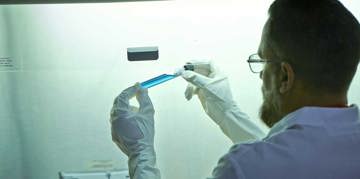 Scientist holding vial with blue liquid.