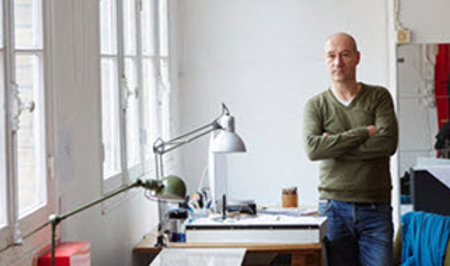 Man standing near desk with arms crossed.
