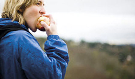 Woman eating an apple outdoors.
